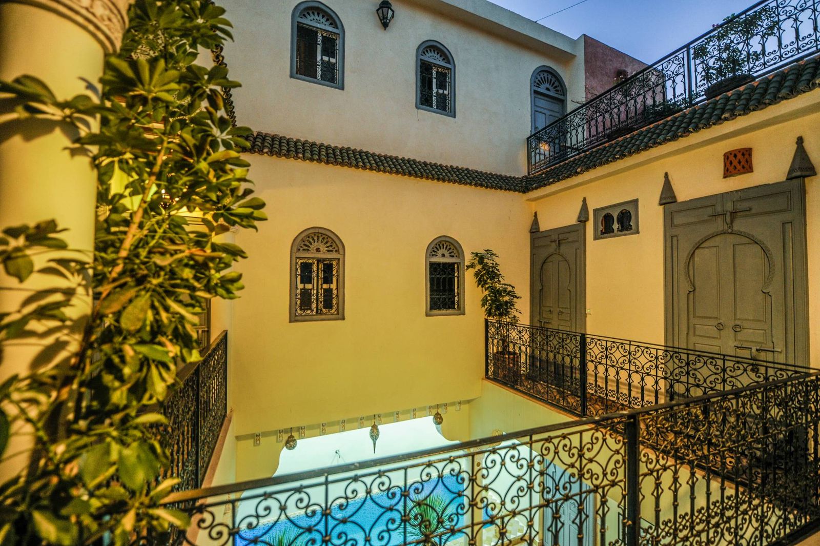 Innenhof des Riad Milouda von der Galerie aus, mit Bogenfenstern, geschmiedeten Geländern und dem Pool darunter